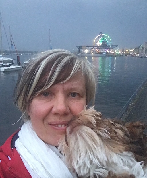 Frau mit Hund im Vordergrund, beleuchtetes Riesenrad der 30. Hanse Sail im Rostocker Stadthafen