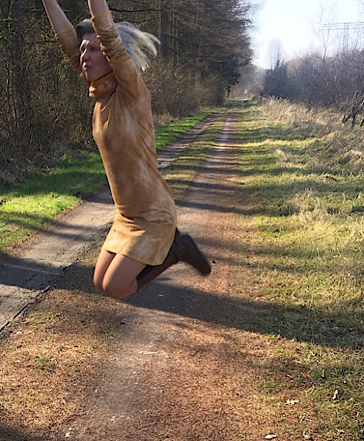 Jahresrückblick 2021: Frau im senfgelben Kleid spring auf dem Waldweg in die Luft