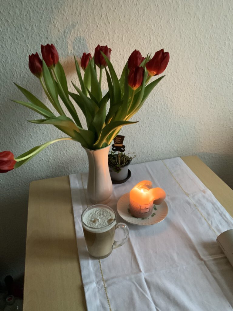Blumen, Kerze und Kaffee auf dem Küchentisch