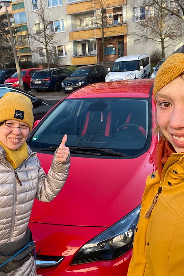 Frau im reifen Alter und junge Frau stehen vor einem roten Opel Astra