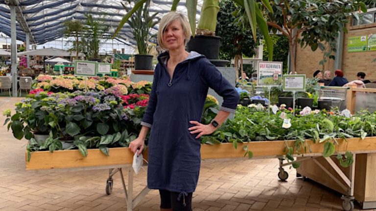 Frau vor blühenden Pflanzen im Gartenfachmarkt