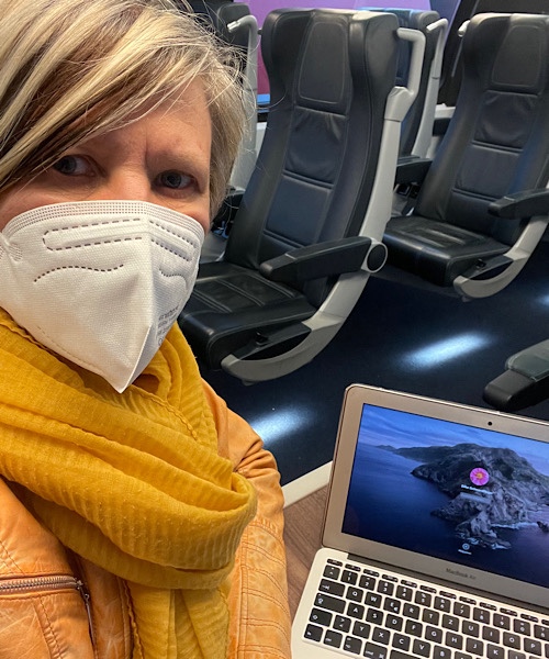 Frau sitzt im Zug mit einem Laptop im Hintergrund