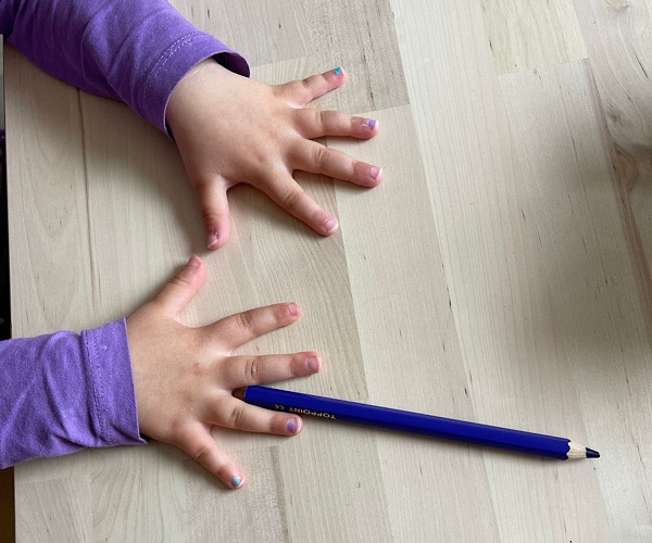 2 Kinderhände mit ausgespreizten Fingern liegen nebeneinander auf dem Tisch verhindern zählendes Rechnen
