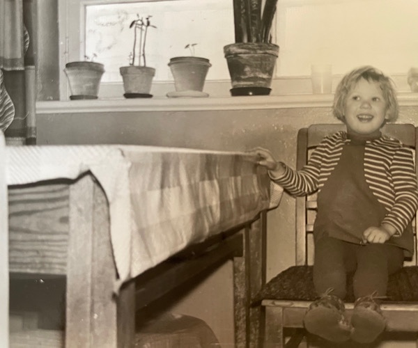 Kleines Mädchen im Kleid sitzt stolz auf einem großen Stuhl in der Küche
