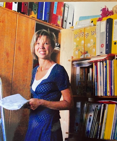 Fünfzigjährige Frau im Arbeitszimmer vor den Bücherregalen und Ordnern im Hintergrund