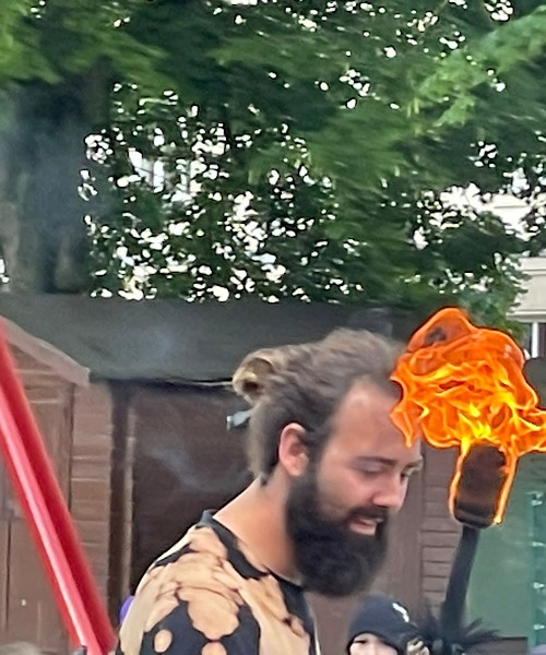 mittelalterlich gekleideter Mann mit einer brennenden Fackel in der Hand während einer Feuershow