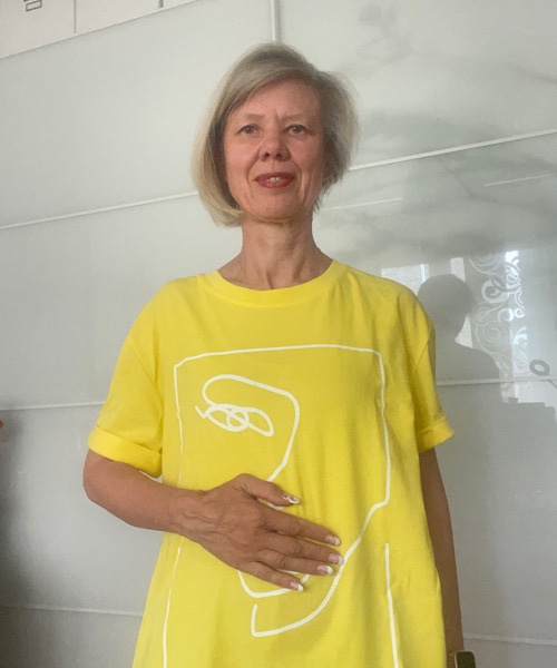 Frau im gelben Shirt streicht sich über den Bauch