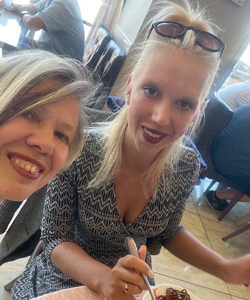 Juli 2022, links Kopf einer blonden Frau, rechts Porträt einer jungen blonden Frau im Kleid am Tisch im Restaurant sitzend