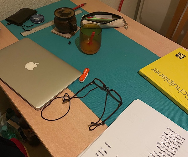 Tisch mit Laptop, Brille, Lehrerkalender, Kaffee, Saft