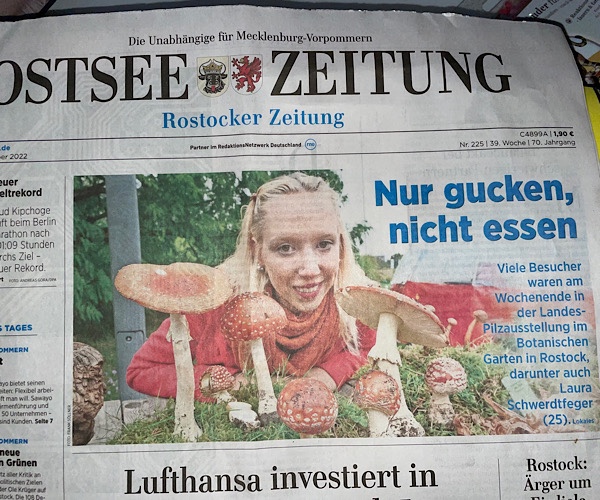 Ostsee Zeitung mit blonder junger Frau im roten Pulli vor Fliegenpilzen auf dem Titelfoto