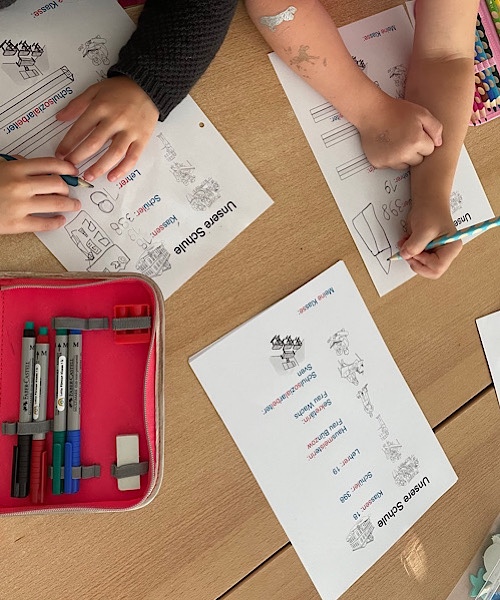 Schüler bearbeiten ein Arbeitsblatt, welches auf dem Schultisch liegt, in den Händen der Kinder ist ein Stift