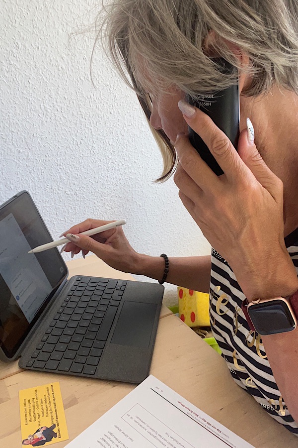 blonde Frau am Telefon vereinbart einen Termin für ein Familiencoaching und trägst diesen in einen Google-Kalender ein