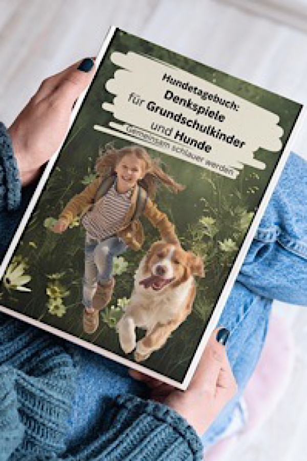 Frau halt auf ihrem Schoß das Buch "Buch: Denkspiele für Grundschulkinder und Hunde"