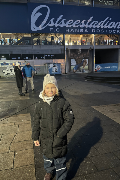 Jahresrückblick 2024; im Hintergrund ist das Ostseestadion zu sehen; im Vordergrund ein Mädchen in schwarzem Wintermantel und hellgrauer Mütze