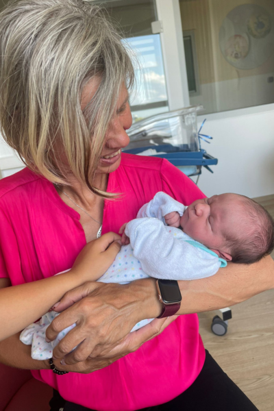 Jahresrückblick 2024; blonde Frau in pinkfarbener Bluse mit einem neugeborenen Baby auf dem Arm