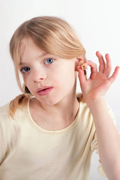 Wie Kinder besser zuhören: Mädchen fasst sich mit den Fingern ans Ohr, so als ob es etwas hören möchte