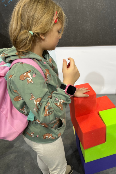 Kindergefühle begleiten: Blondes Mädchen steht vor einem großen Somawürfel und überlegt