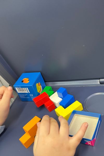Konzentrationstipps Kinder: Hände eines Kindes sind zu sehen, die einen Soma-Würfel zusammen bauen