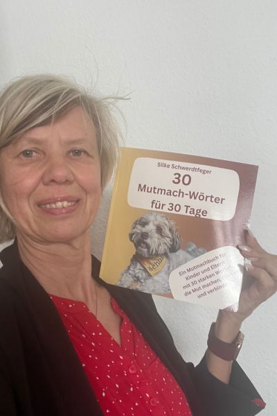 12 von 12 im Juni: blonde Frau zeigt das Buch 30 Mutmach-Wörter für 30 Tage nach oben