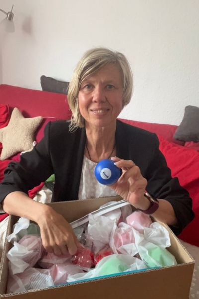 12 von 12 im Juli 2025, blonde Frau im schwarzen Blaser packt ein Paket aus und hält einen Life Kinetik Ball in der Hand