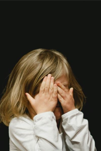 Prüfungsangst Grundschule; Mädchen versteckt sein Gesicht hinter vorgehaltenen Händen