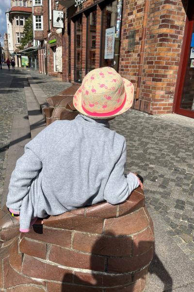 EMDR bei Prüfungsangst, Kind mit Hut sitzt allein auf einem steinernden Schuh mit dem Rücken zum Betrachter