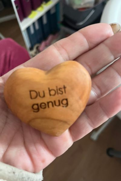 Eltern als Co-Coach: in einer offenen Hand liegt ein Holzherz mit der Aufschrift: Du bist genug