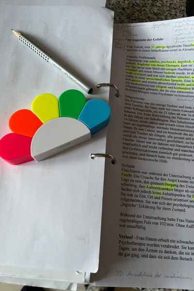 12 von 12; geöffneter Hefter mit weißen Blätter, Textmarker und ein grauer Bleistift liegen auf einem weißen Blatt