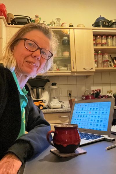 12 von 12; blonde Frau sitzt am Küchentisch mit einer Tasse Kaffee, vor ihr steht ein geöffneter MacBook Air