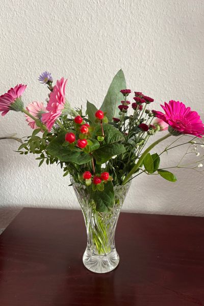 12 von 12; bunter Blumenstrauß mit Gerbera und Grün steht in einer Glasvase auf der Kommode