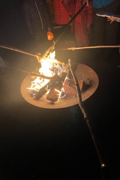 To-Want-Liste 4. Quartal 2025; Feuerschale mit Feuer im Dunklen; Stöcker mit Stockteig werden ins Feuer gehalten