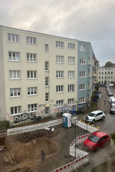 12 von 12 im Oktober 2025; Häuser mit fünf Etagen vor bewölkten Himmel; im Vordergrund eine Baustelle