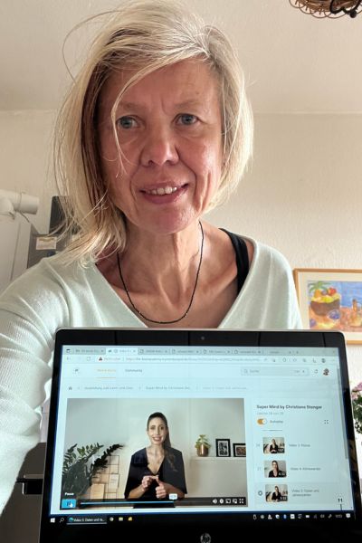 12 von 12 im Oktober 2025; blonde Frau mit mittellangen Haaren steht hinter einem Laptop, indem eine Frau zu sehen ist, die Gedächtnistraining erklärt