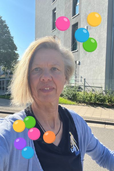 Was ich mit Sorglos lernen bewirken will: blonde Frau im blauen Life Kinetik T-Shirt und bunten Bällen