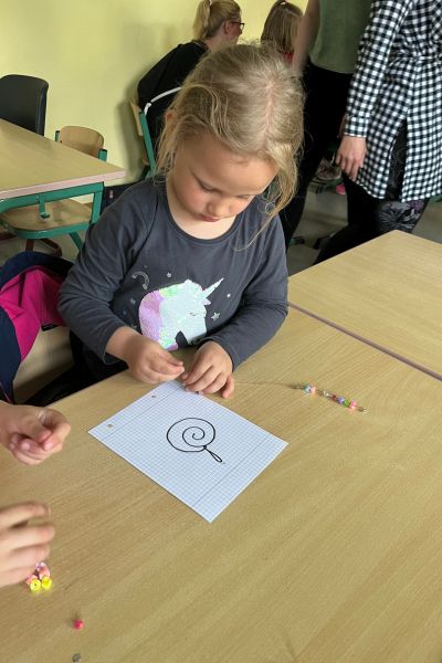 stressfreie Lernroutine ADHS Kind; Kind sitzt am Schultisch, hält einen Stift in der Hand und zeichnet auf einem Blatt Papier