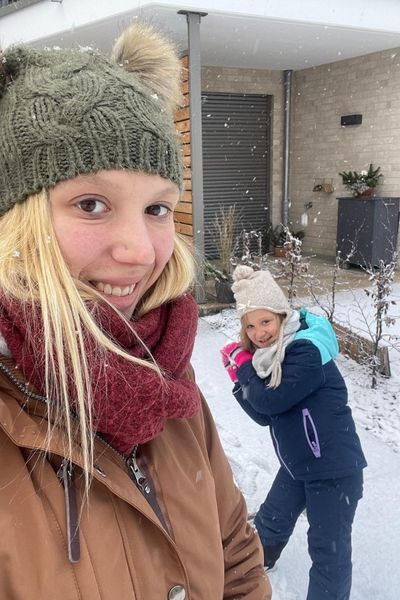 Frau in dicker Jacke mit Mütze und siebenjähriges Kind im Schnee