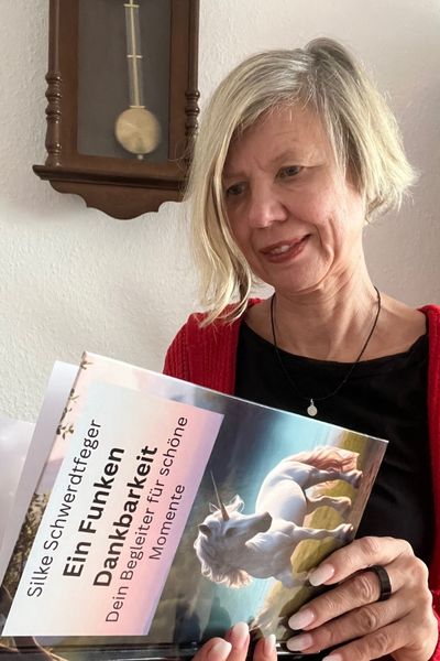 blonde Frau mit dem Buch von Silke Schwerdtfeger: "Ein Funken Dankbarkeit" in der Hand