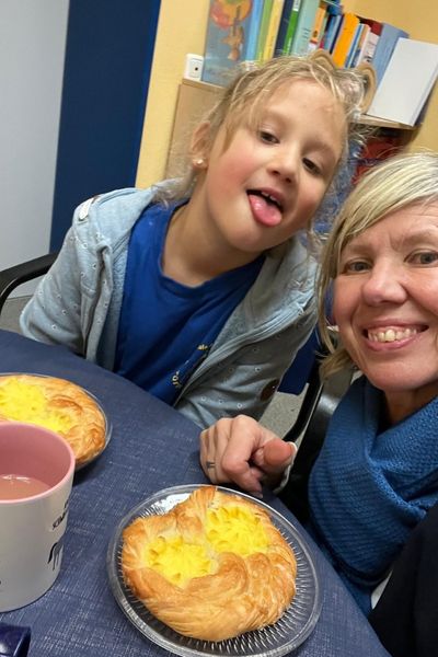 Frau und Mädchen am runden Tisch mit zwei Puddingplundern 