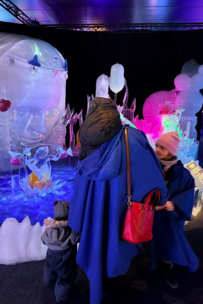 Monatsrückblick Januar 2026: Omi mit Enkelsohn und Enkeltochter in der Ansicht von hinten vor geschnitzten Eisfiguren aus der Märchenwelt