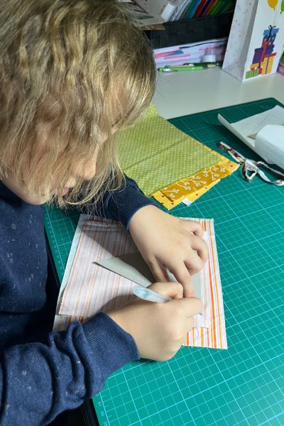 Kind lernt trotz Üben nicht: Kind steht am Tisch und reißt eine Schablone an