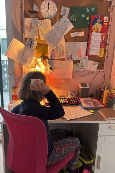 Ausdauer lernen Kind: Kind sitzt am Schreibtisch und will ein geknülltes Papier werfen