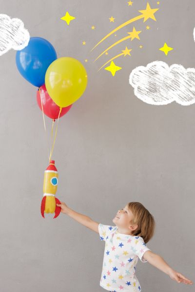 Lernprobleme und Freunde: Mädchen hält je einen roten, gelben und blauen Luftballon nach oben, an der Wand befinden sich Wolken und Sterne