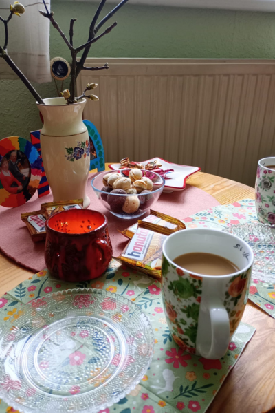 12 von 12 im April 2026: gedeckter Kaffeetisch mit zwei Kaffeetassen, zwei Kuchentellern, Waffeln und einer Kerze 