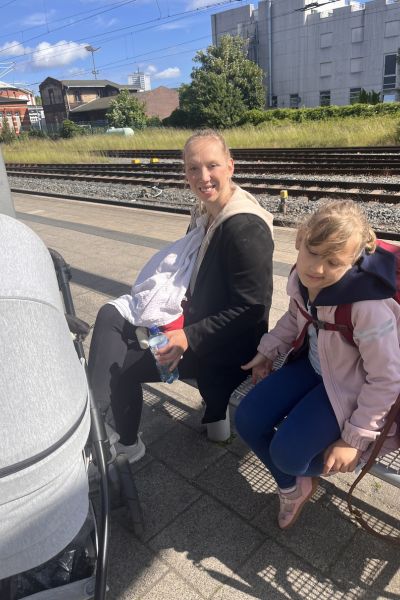 12 von 12 im Juni 2026: Familie mit Mutter, Tochter und Baby auf dem Arm sitzend auf einer Bank auf dem Bahnhof