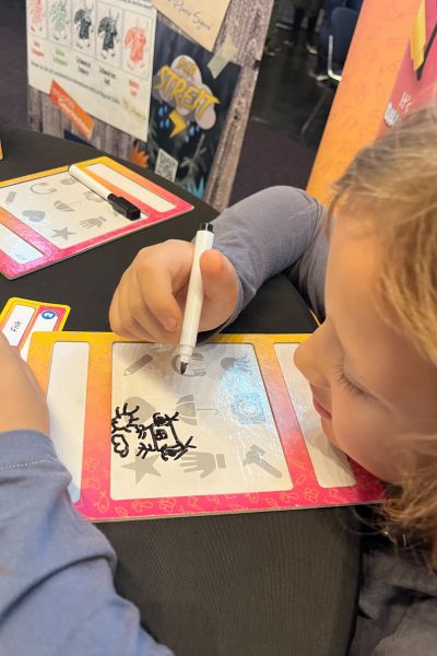 Kind lernt trotz Üben nicht: Kind liegt und malt mit einem Folienstift auf einer Tafel