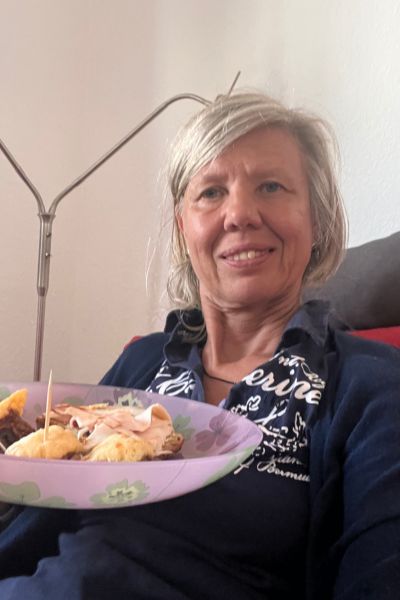 12 von 12 im August 2026: Frau Mitte fünfzig sitzt auf dem Sofa mit einem Teller mit gefüllten Champignons in der Hand