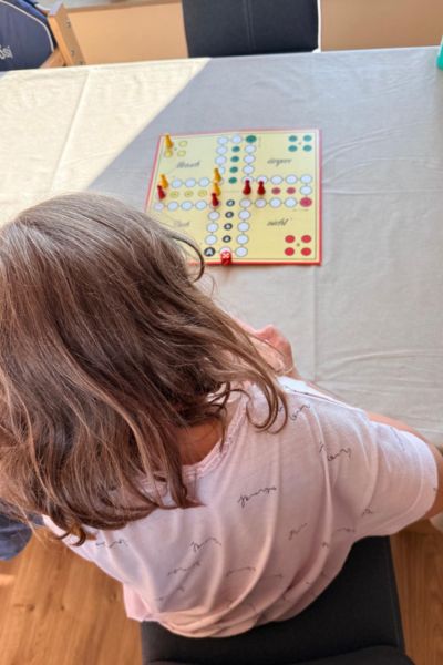 Bucket List fürs Leben: blondes Mädchen in der Rückansicht sitzt vor einem Mensch-ärgere-dich-nicht Spiel