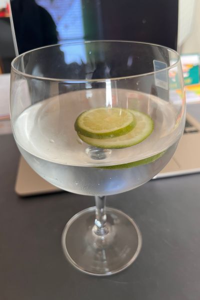 Anwendungsarten ätherischer Öle: ein Glas Wasser mit Zitrone und Limette und einem Tropfen ätherisches Öl "Grüne Mandarine"