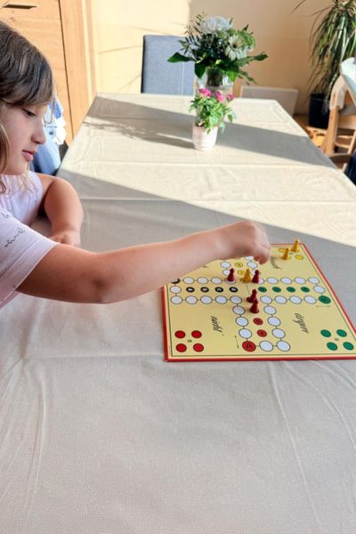 Konzentration fördern mit ätherischen Ölen: Kind sitzt am Tisch vor einem Mensch-ärgere-dich-nicht-Spiel