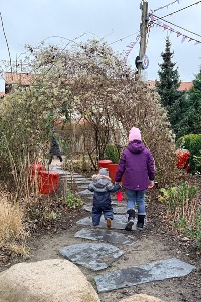 lernimpulse für kinder mit lernproblemen: achtjähriges Mädchen geht mit ihrem zweijährigen Bruder an der Hand